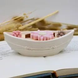 Bougie parfumée avec des fleurs et pot en jesmonite en forme de bateau